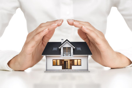 Home protection concept, close up of female hands covering modern houseの写真素材