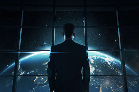 Abstract image of young, successful businessman looking at the earth at nightの写真素材