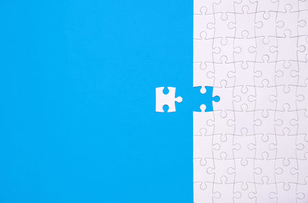 Unfinished white jigsaw puzzle isolated on blue background with copy spaceの写真素材