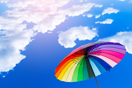 Rainbow umbrella against a bright sky.の写真素材