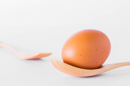 Egg and wooden spoon isolated on white background.の写真素材