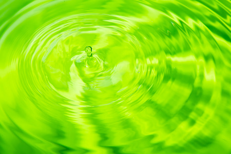 Water droplets off the surface into a circle and a colorful background.の写真素材