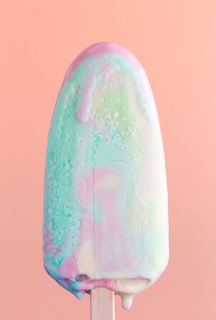 Multicolored ice cream is melting on a pink background.