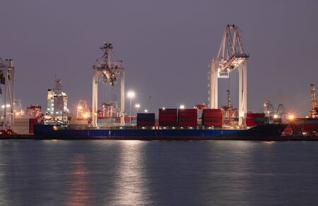 Logistics and container loading by large barges by sea in a harbor full of containers waiting to be...