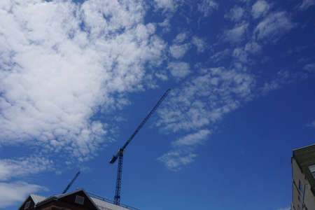 A vertical view of a lifting crane with a background of blue cloudy sky