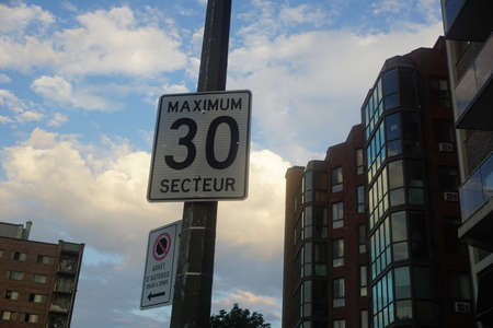 A traffic sign speed limit of 30 Km/hr in a sector with a background of a cloudy blue sky. No stop...