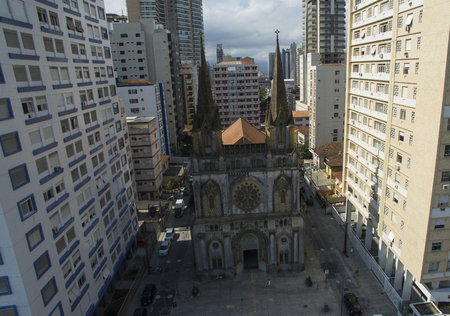 Ancient catholic church surrounded by big building in big cityの写真素材