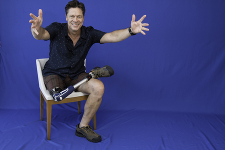 Middle-aged man with physical disability, happy with life sitting on the chairの写真素材