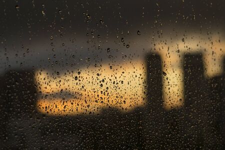 Rain drops on window with blurry background of the city