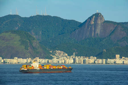Cargo ship arriving in Rio de Janeiro with the statue of Christ the Redeemer, mountains, hills and Copacabana beach in the backgroundの写真素材