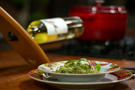 Colorful dish with pesto risotto. White wine and pot in the background.の写真素材