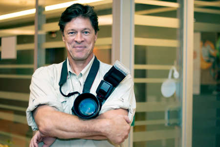 Smiling photographer with his camera. A handsome photographer smiling at the camera.の写真素材
