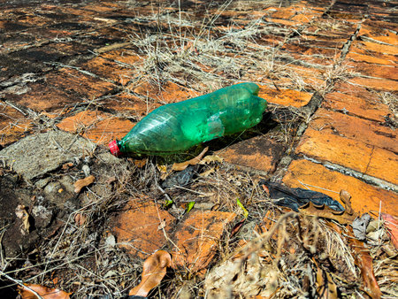 The plastic bottle is thrown away as trash. A crushed plastic bottle lies on the ground.の写真素材