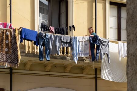 Sicily, Italy - January 08, 2016: Unknown woman hanging clothes on the balcony in Catania.
