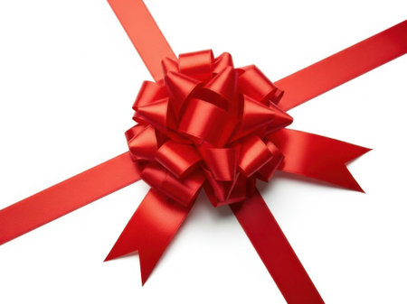 The image features a vibrant red ribbon bow, which is the central focus. The bow is intricately tied with multiple loops and tails, creating a visually appealing and festive appearance. The ribbon is set against a stark white background, which accentuates its rich color and detailed structure. The bow appears to be crafted from a smooth, shiny material, possibly satin, giving it a polished and elegant look. This type of bow is commonly used for gift wrapping, holiday decorations, or special occasions.の素材
