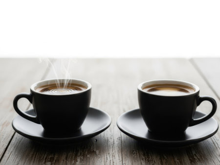 Two black coffee cups on wooden tableの素材