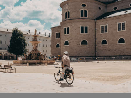 A young man with a bicycle on the square in front of the castle.の写真素材