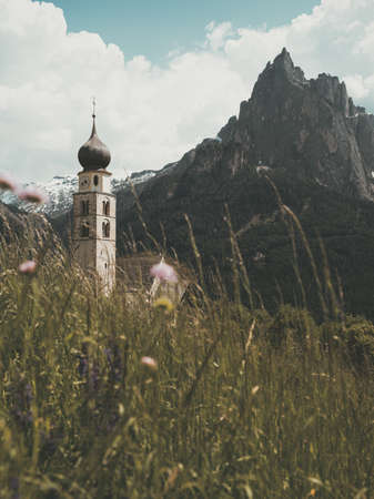 Bell tower of the Church of the Assumption of the Blessed Virgin Mary on the background of the Dolomitesの写真素材