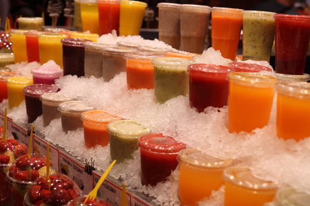 Fresh and healthy fruit juice in closed plastic cups on cold iceの写真素材