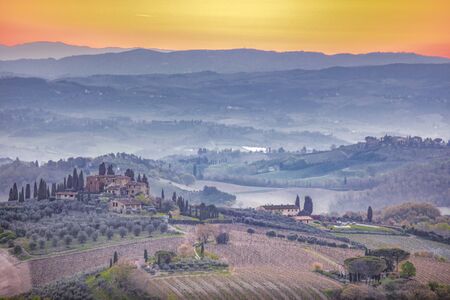 Tuscan sunrise over the fog laden valleys and the cypress lined villas of San Gimignano.