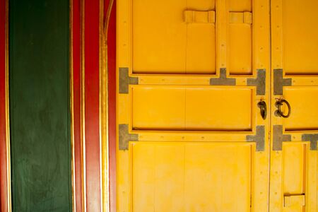 closed, yellow, wooden door against green wallの写真素材