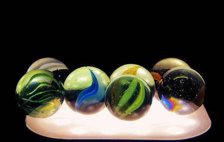 Close-up shot of glass marbles with light underneath. Diversity of the color of marbles