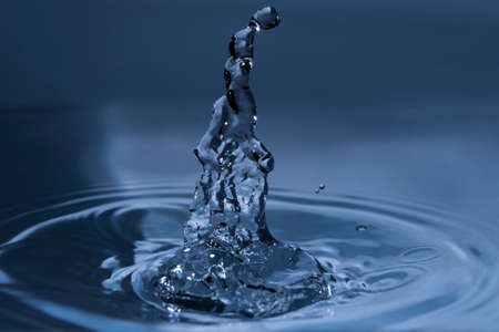 Splashing water drops causing wavy water surfaceの写真素材