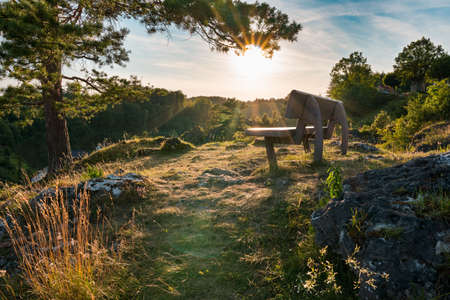 Bench on rock hillside of Franconian Switzerland, sunset on summer eveningの写真素材