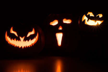 Three carved pumpkins glowing in the darkの写真素材