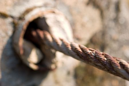 A rusty metal cable entering a concrete holeの写真素材