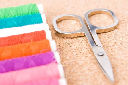 Rolls of colorful cotton with selective  focus on the scissors