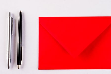 Two pens and a red envelope on a white backgroundの写真素材