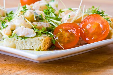 Prawn, cress and tomato sandwich on a white plateの写真素材
