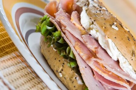 Bagel with freshly cut honey roasted ham and cream cheese on a plateの写真素材