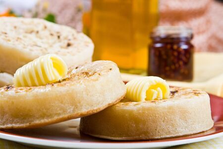 Two hot crumpets on a plate (jam in the background)の写真素材