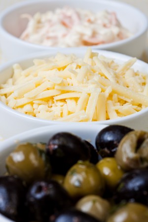 Three dishes of coleslaw, grated cheese and olivesの写真素材