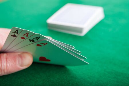 Four aces with a pack of playing cards in the background