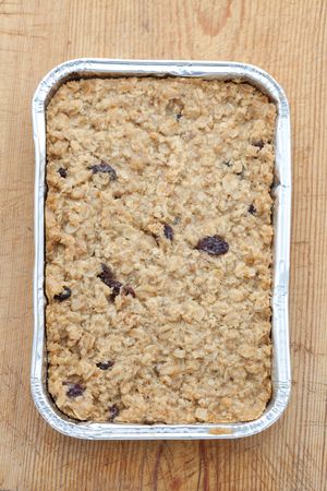 Flapjack in a silver baking tray on a wooden boardの写真素材