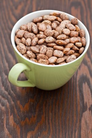 Green cup with pinto beans on a wooden tray
