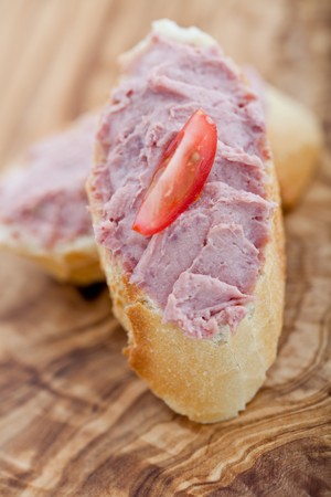 Two baguette slices with liver and apple pate and a thin tomato slice on top. Shallow DOFの写真素材
