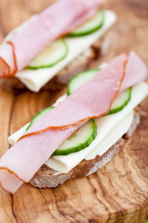 Delicious appetizer of cheese, ham and cucumber on rye bread. Shallow DOFの写真素材