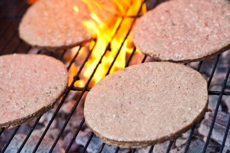 Large beefburgers cooking on a BBQの写真素材