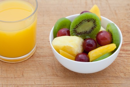 Healthy breakfast of fruit salad and orange juice on a wooden boardの写真素材