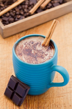 Mug of hot chocolate with a cinnamon stick and four pieces of dark chocolate. Shallow DOFの写真素材
