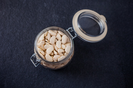 Glass jar full with butter beans on a slate background