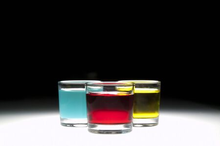 Three shot glasses filled with colored alcohol, black background.の写真素材