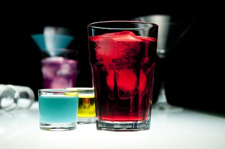 Glasses filled with colored alcohol, black background.の写真素材