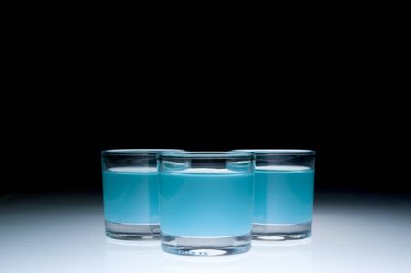 Three shot glasses filled with colored alcohol, black background.の写真素材