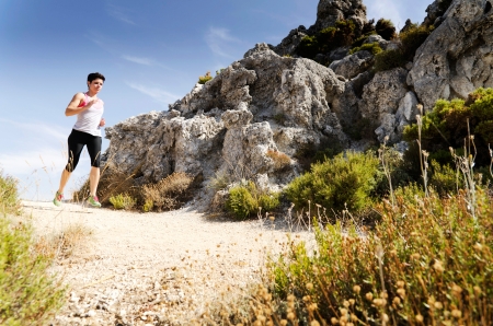 Young woman running on a dry mountain path.の写真素材