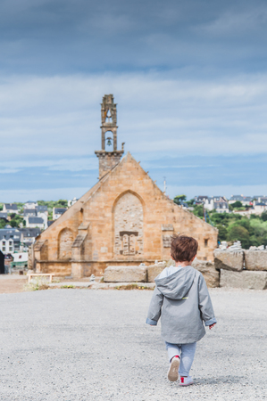 Child walking in front of Notre Dame de Rocamadour church in Camaret-sur-mer, Finistere, Brittany, Franceの写真素材